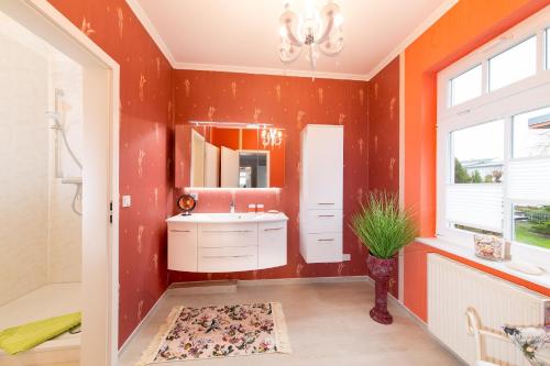 a bathroom with orange walls and a sink and a mirror at Haus Mozart in Binz