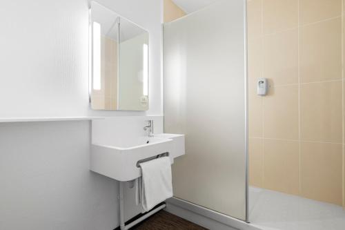 La salle de bains blanche est pourvue d'un lavabo et d'un miroir. dans l'établissement B&B HOTEL Lyon Centre Part-dieu Gambetta, à Lyon