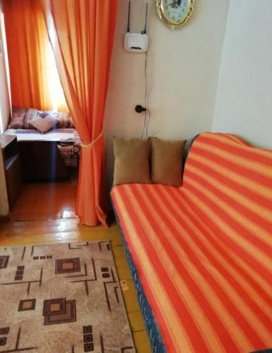 RubtsovskにあるApartment on Altaiskaia 181のオレンジのストライプシーツが施されたベッド1台が備わる客室です。