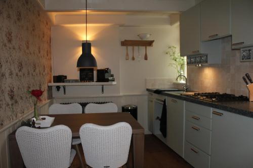 een keuken met een houten tafel en witte stoelen bij 't Stee fan Anne P. in Rottevalle