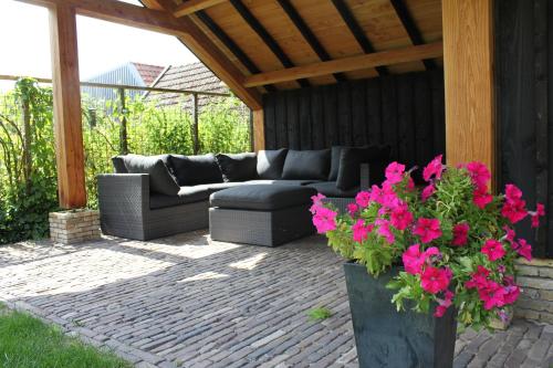 a patio with a couch and pink flowers in a vase at 't Stee fan Anne P. in Rottevalle