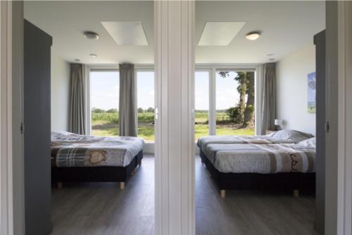 two beds in a room with two windows at Onderlandhuis 38 in Chaam