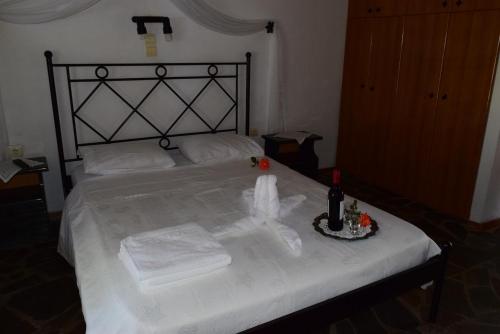 ein Bett mit weißer Bettwäsche und einer Flasche Wein darauf in der Unterkunft Panoramma Hause, Kampos Evdilou,Ikaria in Évdilos