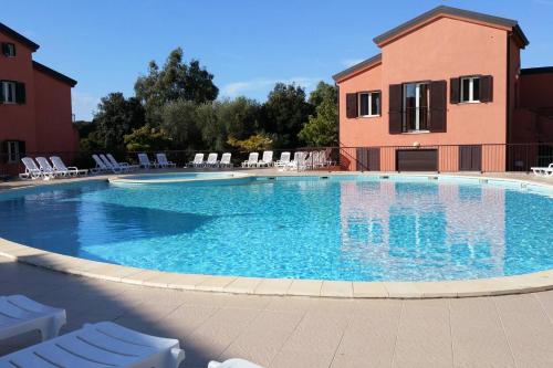 une grande piscine avec des chaises et un bâtiment dans l'établissement Appartement June, à Palasca