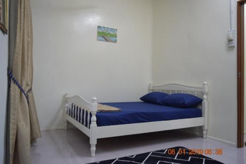 a bedroom with a white bed with blue sheets at RILEK-RILEK HOMESTAY in Jertih