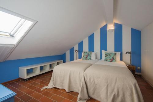 two beds in a room with blue and white stripes at Villa Eira in Vila Nova de Milfontes