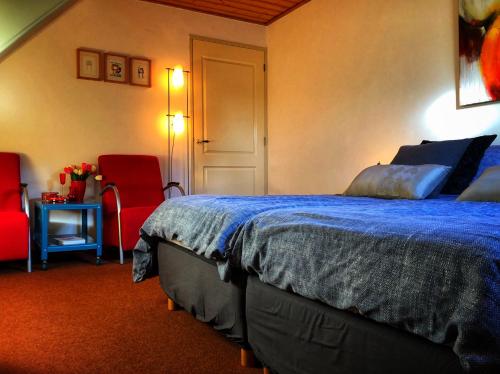 a bedroom with a bed and two red chairs at B&B Zandhuizen in Zandhuizen