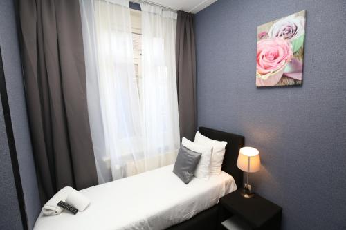 a bedroom with two beds and a window with pink roses at Hotel Flipper Amsterdam in Amsterdam