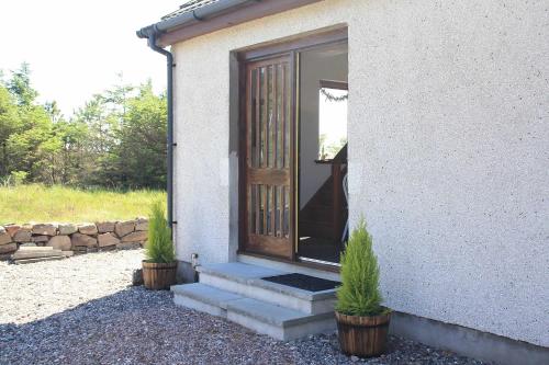 une porte d'une maison avec deux plantes en pot dans l'établissement Shiskine, à Gairloch