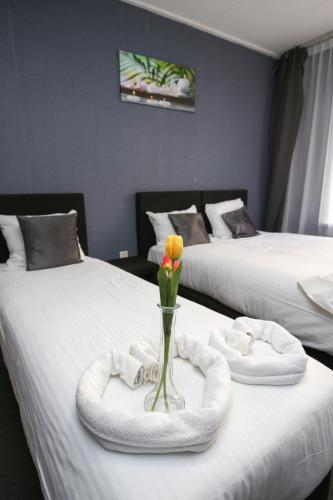 a room with two beds with a vase with a flower in it at Hotel Flipper Amsterdam in Amsterdam