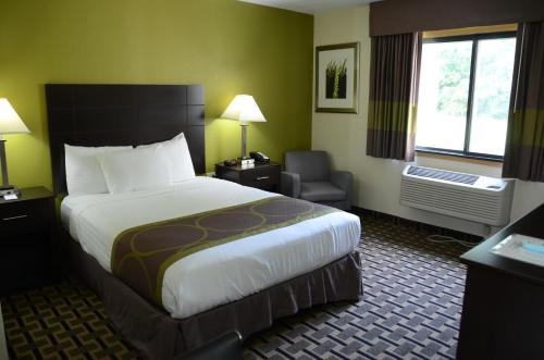 a hotel room with a large bed and a chair at AmericInn by Wyndham West Burlington in West Burlington