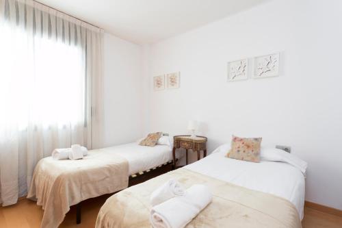 two beds in a room with white walls at 1217 - POOL AND BEACH NICE APARTMENT II in Barcelona