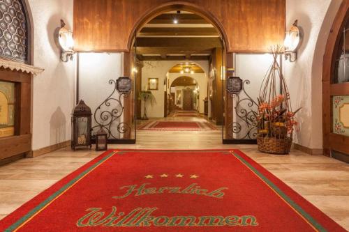 un pasillo del hotel con una alfombra roja de bienvenida en el suelo en Hotel Donnerhof, en Fulpmes