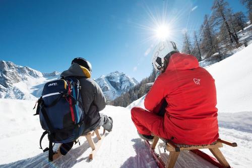 two people sitting on a sled in the snow at Hotel Donnerhof in Fulpmes