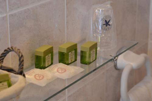 ein Glasregal in einem Badezimmer mit grünen Kisten darauf in der Unterkunft The Originals City, Hôtel Le Cheval Rouge, Tours Ouest (Inter-Hotel) in Villandry