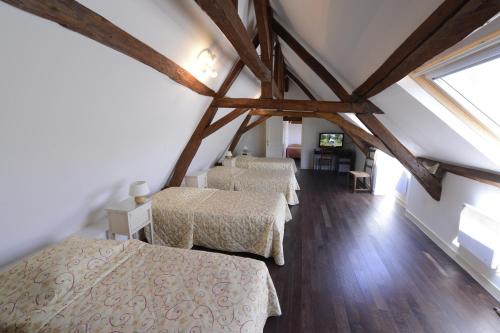 a room with three beds in a attic at The Originals City, Hôtel Le Cheval Rouge, Tours Ouest in Villandry