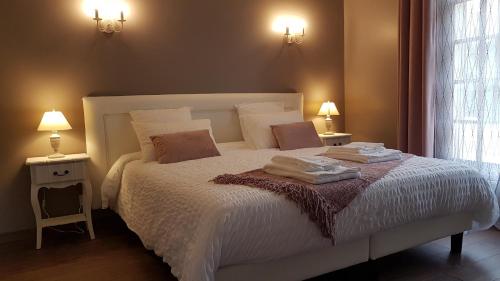 a bedroom with a large white bed with two lamps at Le Clos Magedon in Médan