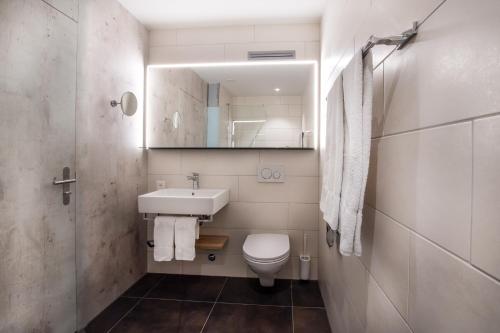 a bathroom with a toilet and a sink and a mirror at Hotel sleep&stay - Self Check-in in Eglisau