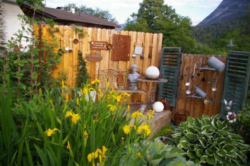 a garden with yellow flowers and a wooden fence at Thalerhof in Roppen