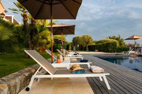 a row of lounge chairs and an umbrella next to a pool at TERRE DE REVE in Le Rouret
