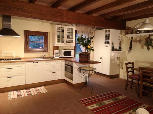 a kitchen with white cabinets and a table at Rose Cottage Tuscany in Fosdinovo