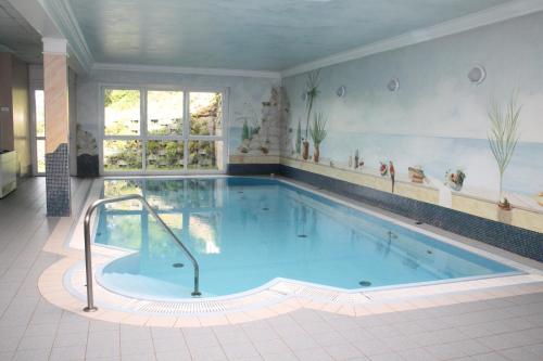 a large swimming pool in a room with a large tub at Vitalhotel Sonnblick in Egg am Faaker See