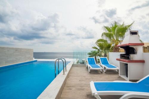 a resort swimming pool with chairs and a view of the ocean at The Sea-Bank Villa Apartments in Marsaskala