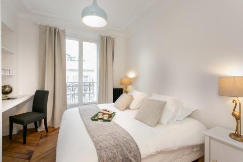 Schlafzimmer mit einem weißen Bett, einem Schreibtisch und einem Fenster in der Unterkunft La Résidence du Sénateur in Paris