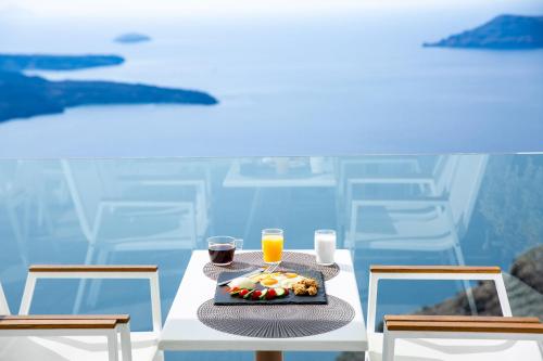 a table with a plate of food and two glasses of orange juice at Pearl on the Cliff Hotel & Suites by Pearl Hotel Collection in Imerovigli