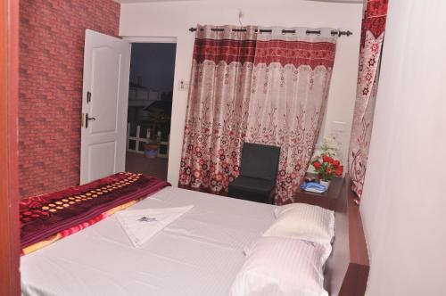 um quarto com uma cama e uma janela em Drizzle Drop Inn em Ooty