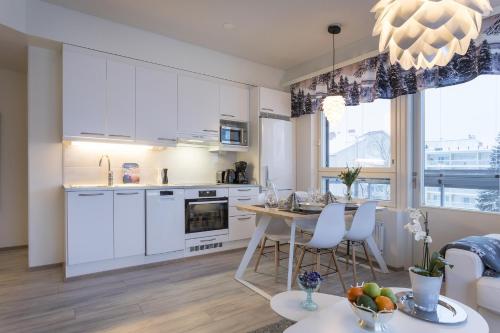 Una cocina con gabinetes blancos y una mesa con sillas. en Vasko luxurious suites, Ahola, en Rovaniemi