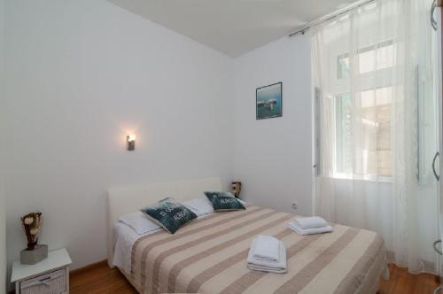 ein weißes Schlafzimmer mit einem Bett mit zwei Handtüchern darauf in der Unterkunft Split Center Apartment in Split
