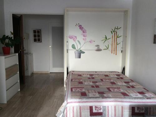 Un dormitorio con una cama y una pared con flores. en Appartement Dolce Vita, en Cagnes-sur-Mer