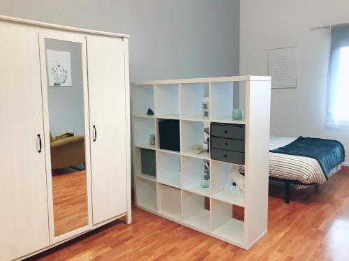 uma prateleira de livros brancos num quarto com uma cama em MONTECERRAO I (GARAJE Y WIFI GRATIS) em Oviedo