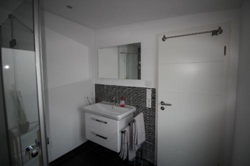 uma casa de banho branca com um lavatório e um espelho em Ferienwohnung Schamne em Gernsbach