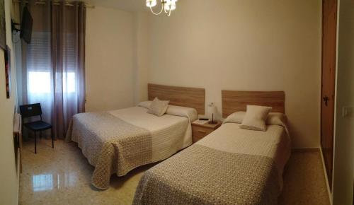 sypialnia z 2 łóżkami i żyrandolem w obiekcie Hostal Tilos w Maladze