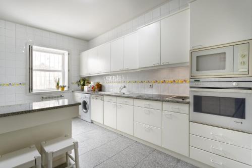 a white kitchen with white cabinets and a microwave at Casas Da Formiga - Riverview Terrace and Pool in Porto