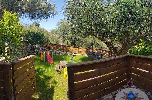 a backyard with a wooden fence and a playground at Rania Apartments in Agios Nikitas