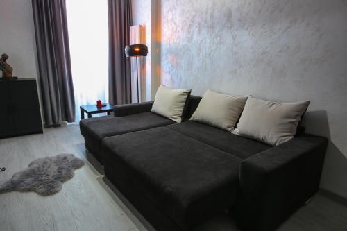 un sofá negro en una sala de estar con un gato en el suelo en Simona Maria, en Bucarest