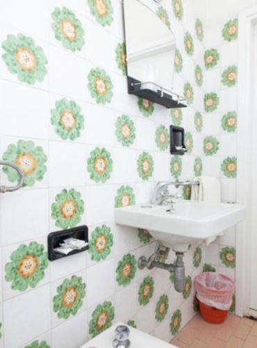 a bathroom with a sink and flowers on the wall at Hotel Ronconi in Rimini