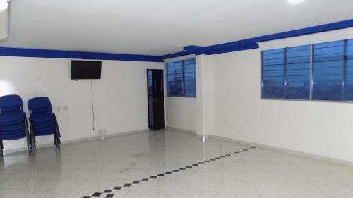 a room with two blue chairs and a television at Hotel Luna Azul in Florencia