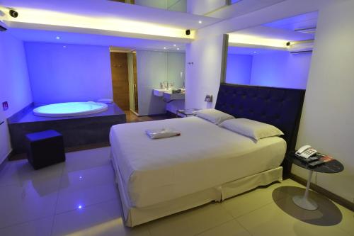 a bedroom with a bed and a tub in a room at Eros Hotel CDU (Adults Only) in Recife