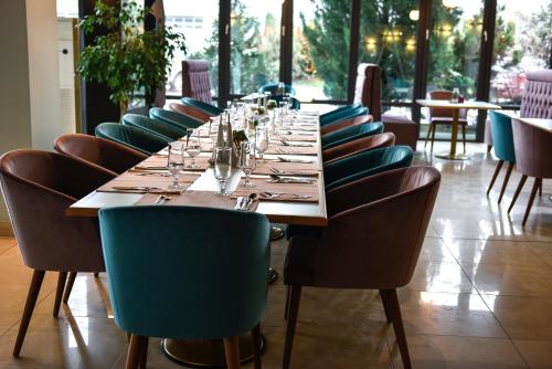 a long table in a restaurant with chairs and glasses at Hotel SunGarden Salin in Turda
