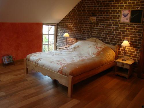 a bedroom with a bed and a brick wall at Gît' Âne Evasion in Le Bec-Thomas