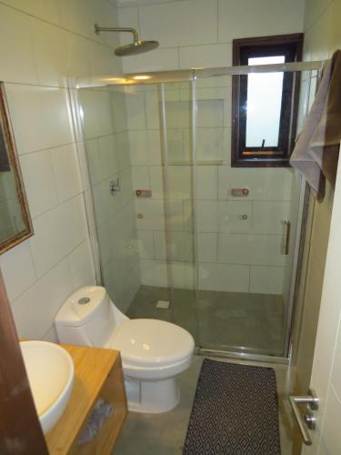 a bathroom with a toilet and a glass shower at Punta Sal Pichilemu in Pichilemu