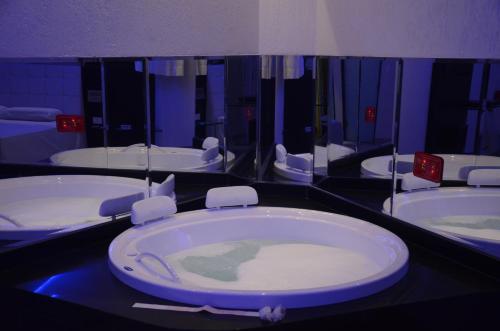 a bathroom with a large tub with a mirror at Eros Hotel - Adult Only in Recife