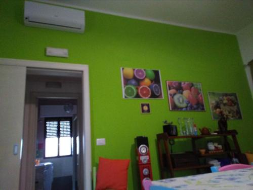 a green room with a bed and some pictures on the wall at Villetta Dote in Casarano