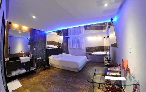 a bedroom with a white bed and a glass table at Eros Hotel - Adult Only in Recife