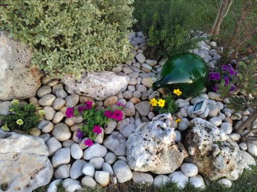 a garden with rocks and flowers and a green glass jar at Villetta Dote in Casarano