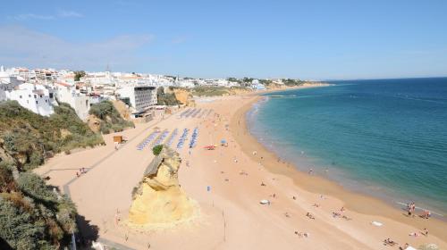Una playa con multitud de gente y el océano. en Rossio, en Albufeira